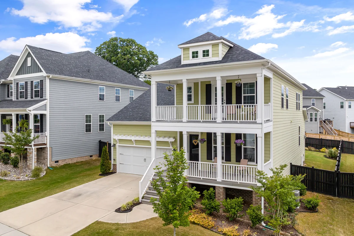 Pale yellow coastal-style home with broad porches and a green front lawn.