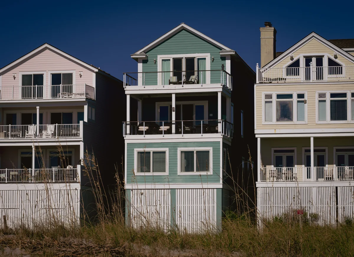 Three raised coastal homes with balconies and wood siding.