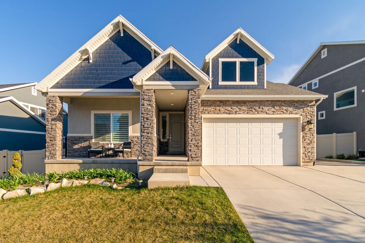 Suburban home with stonework, a covered entry, and attached garage.