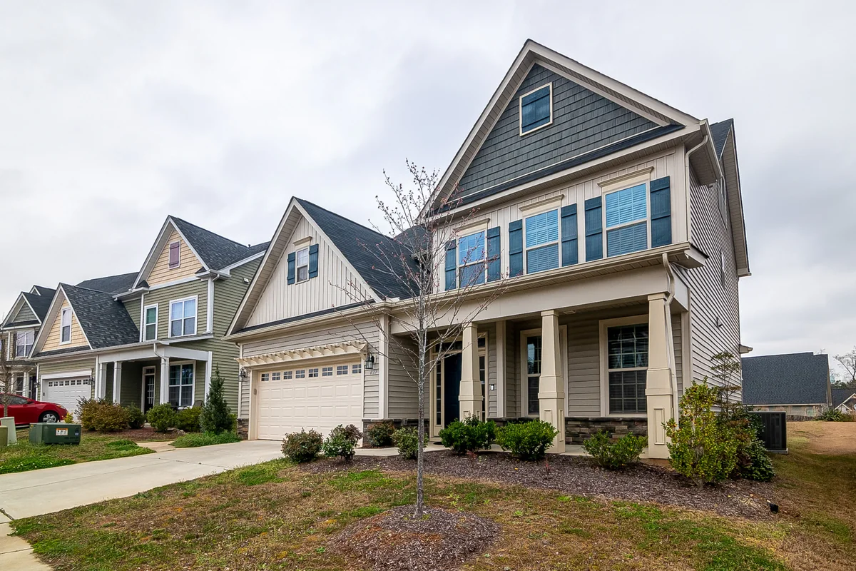 Gray and white home with a steep shingle roof and covered front porch.