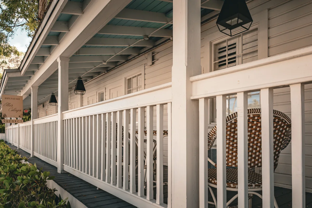 Covered porch with white railings, windows, and a pale blue ceiling.